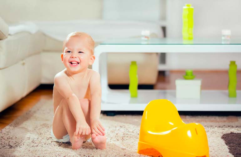 the child is sitting next to the potty