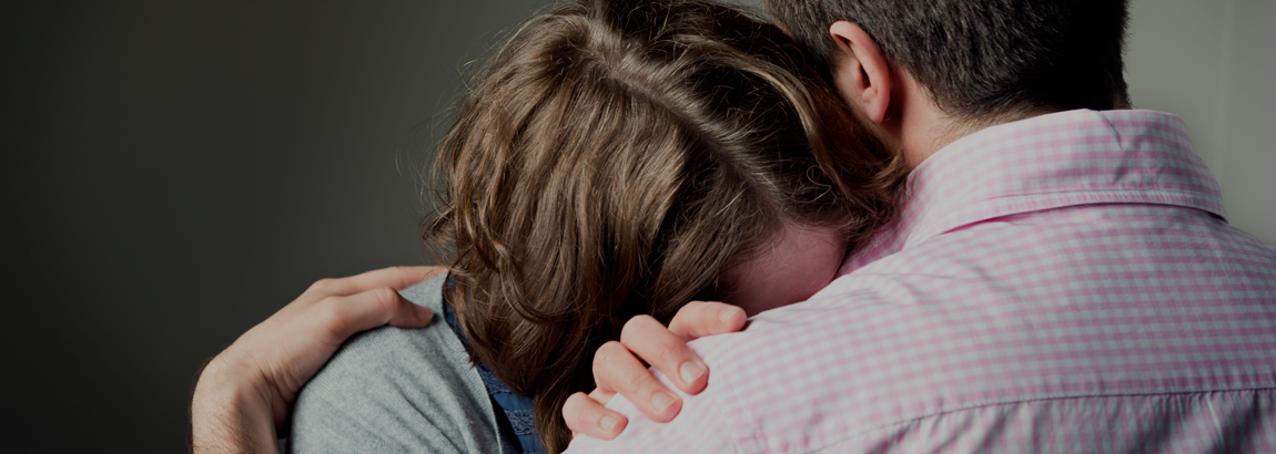 a woman cries on a man’s shoulder